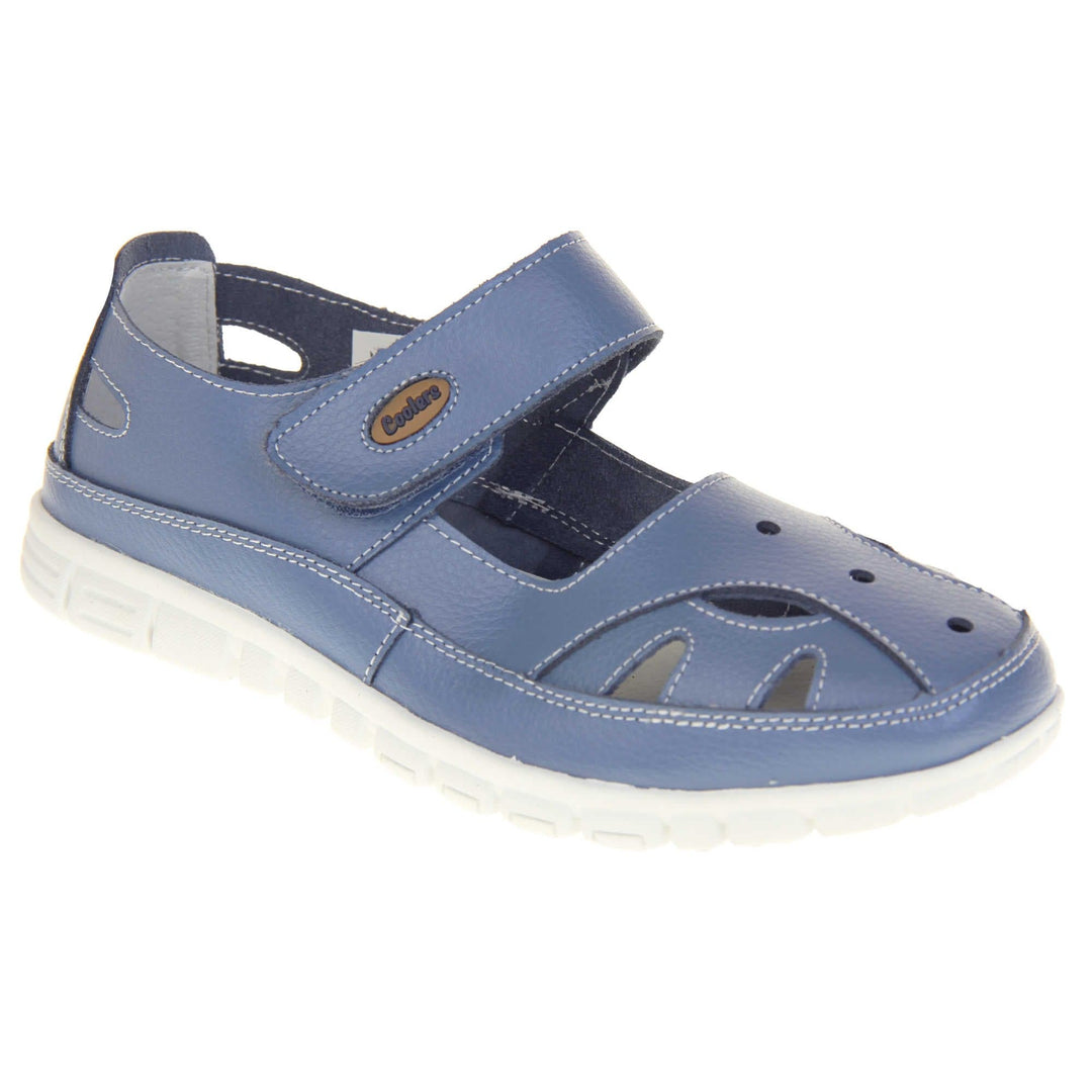 Comfy wide fit sandals. Mary Jane style shoes. Blue leather uppers with white stitching detail. Blue touch fasten strap over the foot with brown oval with Coolers branding on. Cut outs in the middle, edges and heel of the shoes. White sole with grip to the bottom. Right foot at an angle.