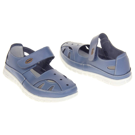Comfy wide fit sandals. Mary Jane style shoes. Blue leather uppers with white stitching detail. Blue touch fasten strap over the foot with brown oval with Coolers branding on. Cut outs in the middle, edges and heel of the shoes. White sole with grip to the bottom. Both shoes about an inch apart at a slight angle facing top to tail.