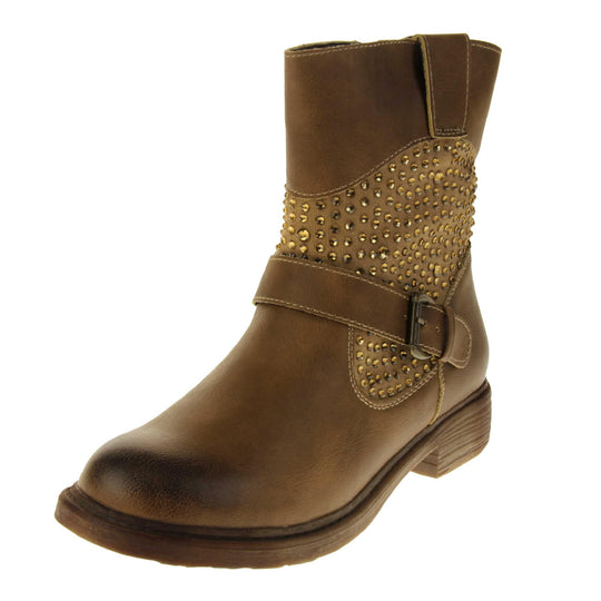 Tan flat ankle boots women. Biker style ankle boot with a tan faux leather upper. Textile panel running around the ankle with gold diamante studs covering it. Single strap with buckle over the top of the ankle. Zip fastening down the inside of the boot. Brown sole with a slight heel. Left foot at an angle.