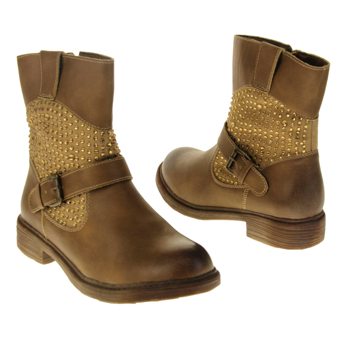 Tan flat ankle boots women. Biker style ankle boot with a tan faux leather upper. Textile panel running around the ankle with gold diamante studs covering it. Single strap with buckle over the top of the ankle. Zip fastening down the inside of the boot. Brown sole with a slight heel. Both feet from a slight angle facing top to tail.