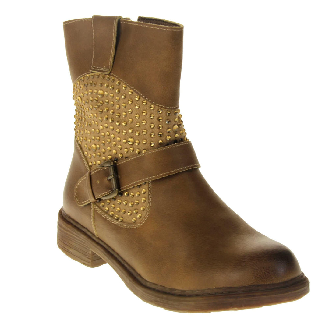Tan flat ankle boots women. Biker style ankle boot with a tan faux leather upper. Textile panel running around the ankle with gold diamante studs covering it. Single strap with buckle over the top of the ankle. Zip fastening down the inside of the boot. Brown sole with a slight heel. Right foot at an angle.