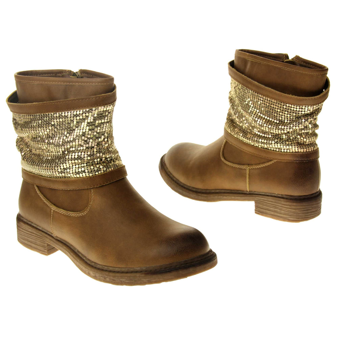 Tan sparkle ankle boots women. Biker style ankle boot with a tan faux leather upper. A thick band of shiny gold chainmail runs around the ankle. Zip fastening down the inside of the boot. Brown sole with a slight heel.  Both feet from a slight angle facing top to tail.