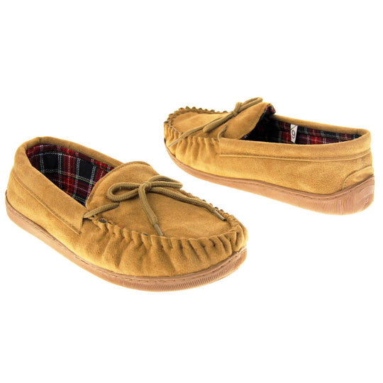 Tartan slippers. Moccasin style slipper with tan suede upper and leather bow to the top. Blue and red tartan plaid lining. Beige synthetic sole. Both shoes spaced apart, facing top to tail at an angle.