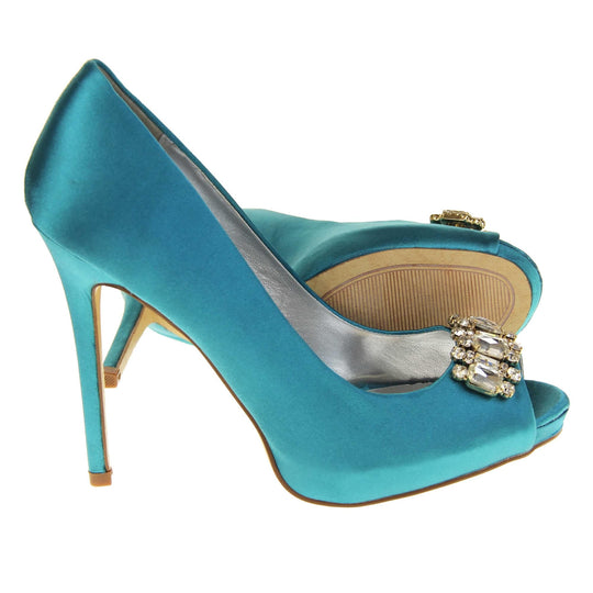 Teal wedding shoes. Classic women's peep toe high heels with a teal satin upper. Metallic silver insole with Sabatine branding. Teal satin stiletto heel with a cream sole. Diamante cluster detailing across the toes. Both feet from a side profile with the left foot on its side behind the the right foot to show the sole.