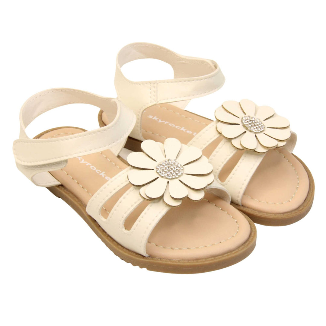 Toddler girl flower sandal. Strappy sandals with white faux leather strappy upper. With around the ankle strap with hook and loop fastening. White flower detailing to the front of the shoe with a diamante middle. Beige coloured insole with Skyrocket branding in white. Brown sole with grip to the bottom. Both feet together at an angle.