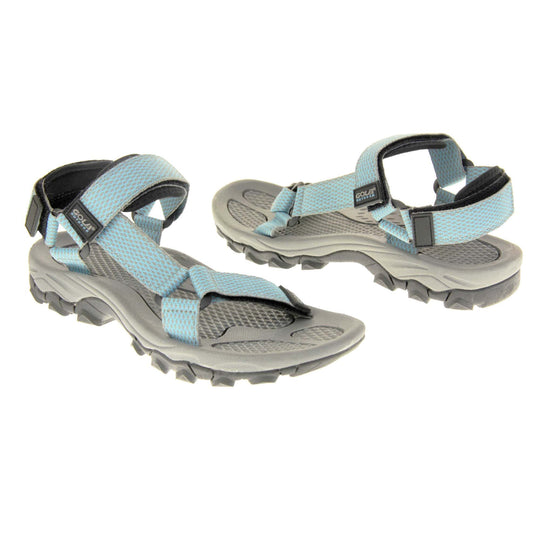 Walking sandals women. Womens sporty style sandals. Grey textile straps with blue criss-cross pattern. Black padding to the heel and over foot strap. Touch fasten strap around the heel. Black Gola branding to the ankle of the sandal. Grey textile lining and black sole with chunky grip to the base. Both feet at an angle facing top to tail.