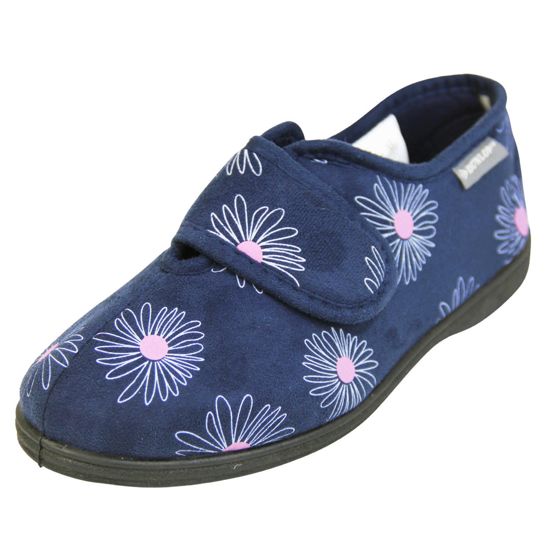 Washable slippers womens. Ladies full back slipper. Navy blue upper with white daisy design and bright pink for the middle of the flowers. Touch fasten strap over the top of the foot to adjust the fit. Matching blue textile lining and sole. Left foot at an angle.