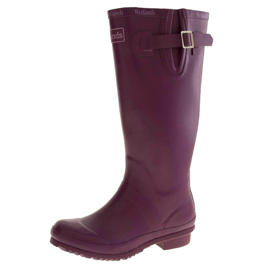 Womens Wellies. Purple rubber waterproof wellington boots. Just below knee height. With a small heel and deep tread to the sole. Pink Wetlands Brand to the front of the boot near the top. Wetlands written in Lilac numerous times around the rim of the boot. Side strap with buckle to adjust the calf width. Textile lining to the inside of the boot. Left foot at an angle.