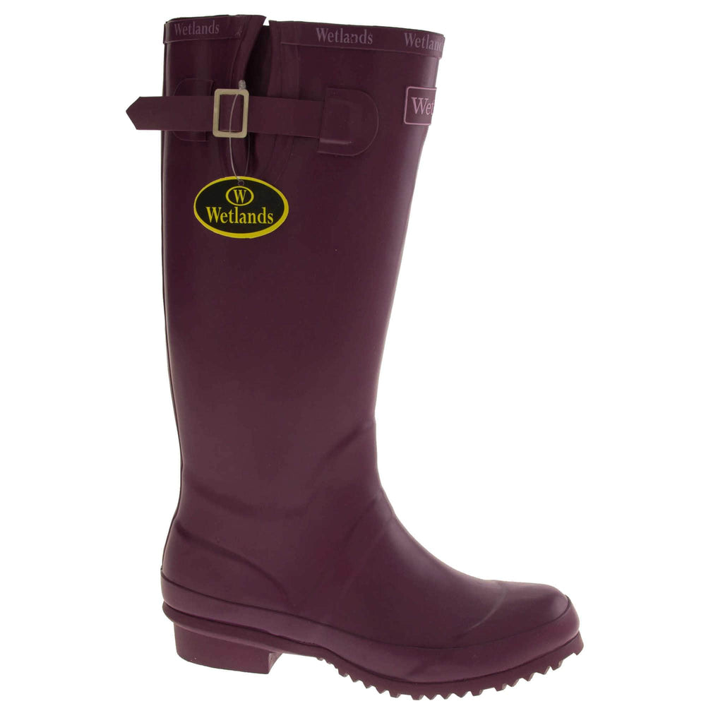 Womens Wellies. Purple rubber waterproof wellington boots. Just below knee height. With a small heel and deep tread to the sole. Pink Wetlands Brand to the front of the boot near the top. Wetlands written in Lilac numerous times around the rim of the boot. Side strap with buckle to adjust the calf width. Textile lining to the inside of the boot. Right foot at an angle.