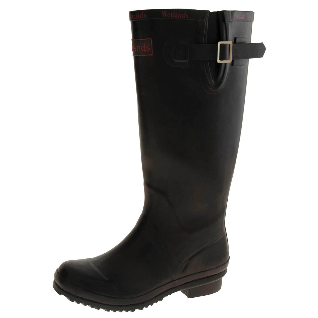 Womens Wellies. Black rubber waterproof wellington boots. Just below knee height. With a small heel and deep tread to the sole. Red Wetlands Brand to the front of the boot near the top. Wetlands written in red numerous times around the rim of the boot. Side strap with buckle to adjust the calf width. Textile lining to the inside of the boot. Left foot at an angle.