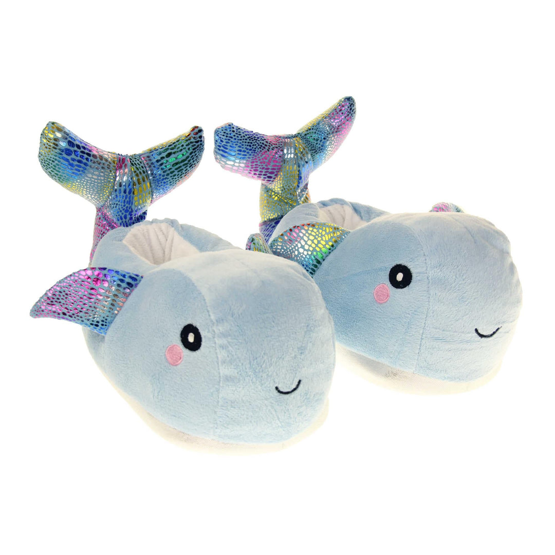 Whale slippers. Womens padded slippers shaped like a whale. With a pale blue body and head. Metallic rainbow fins and tail. Both feet together at an angle.