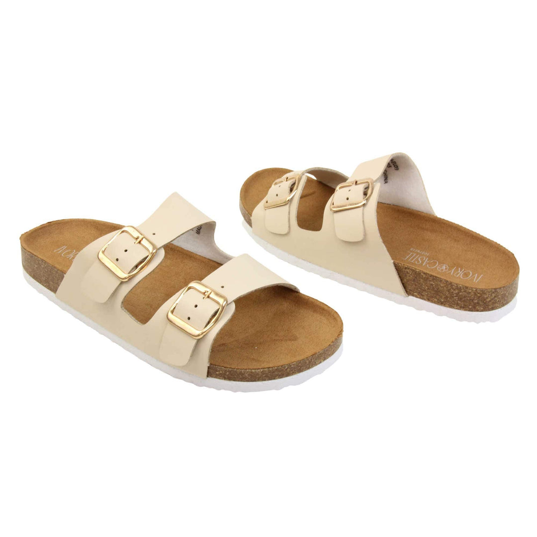White double strap sandals. Womens dual strap slip on sandals. With a white synthetic leather upper with a gold buckle on each strap. Brown faux suede insole with a moulded footbed. Cork effect outsole with white base with grip to the bottom. Both feet at an angle facing top to tail.