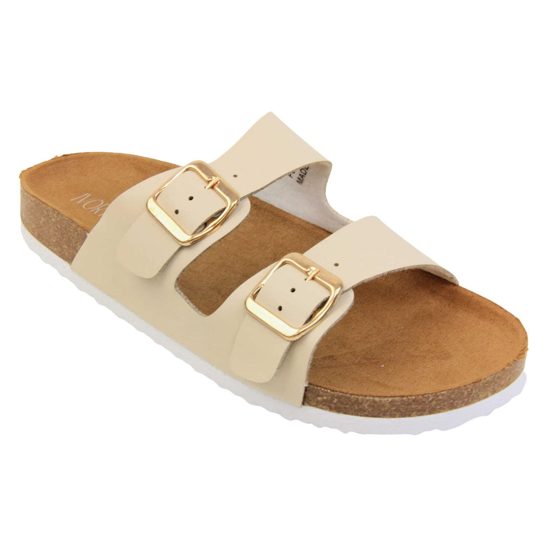 White double strap sandals. Womens dual strap slip on sandals. With a white synthetic leather upper with a gold buckle on each strap. Brown faux suede insole with a moulded footbed. Cork effect outsole with white base with grip to the bottom. Right foot at an angle.