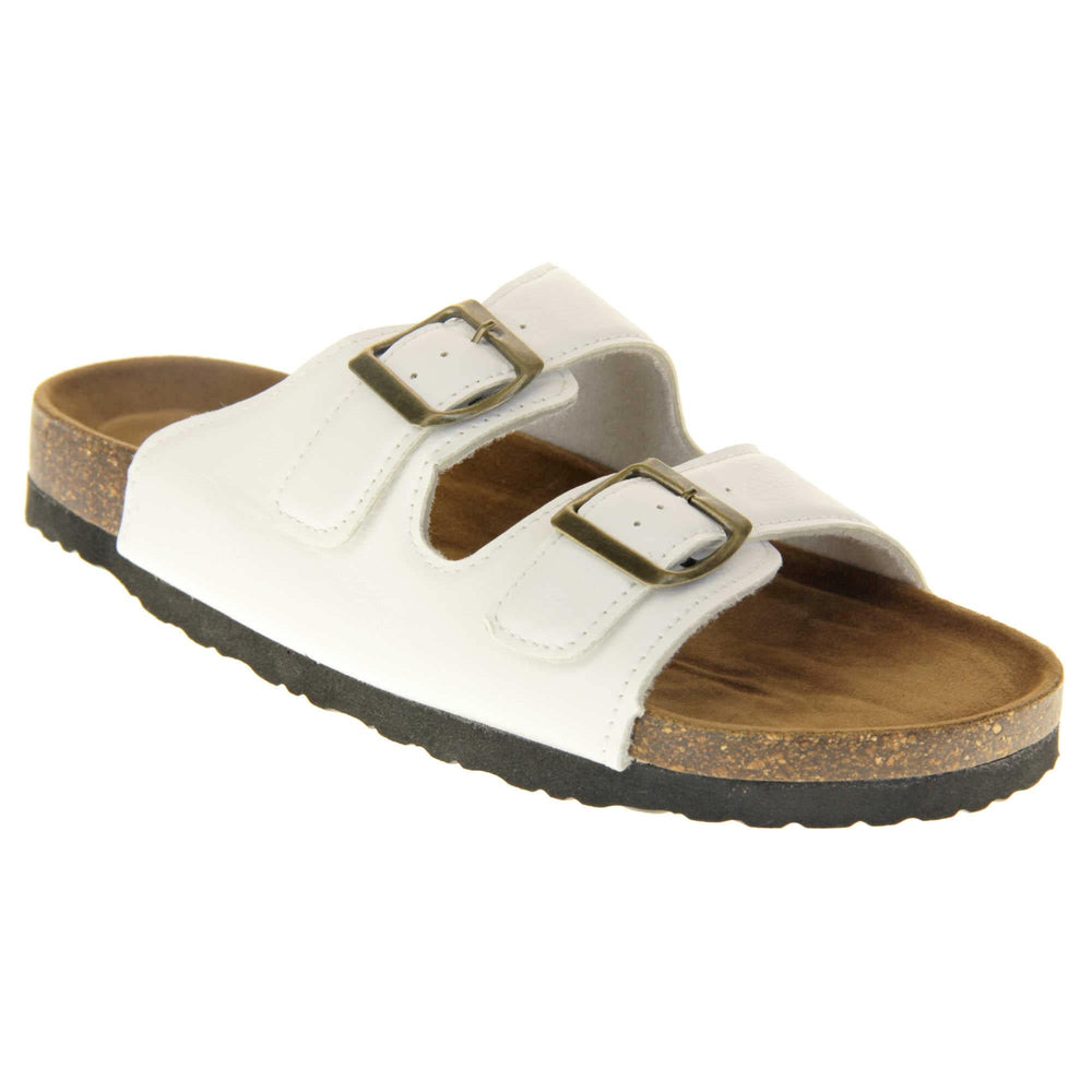 White flat sandals womens. Ladies dual strap slip on sandals. With a white synthetic leather upper with a gold buckle on each strap. Brown faux suede insole with a moulded footbed. Cork effect outsole with black base with grip to the bottom. Right foot at an angle.