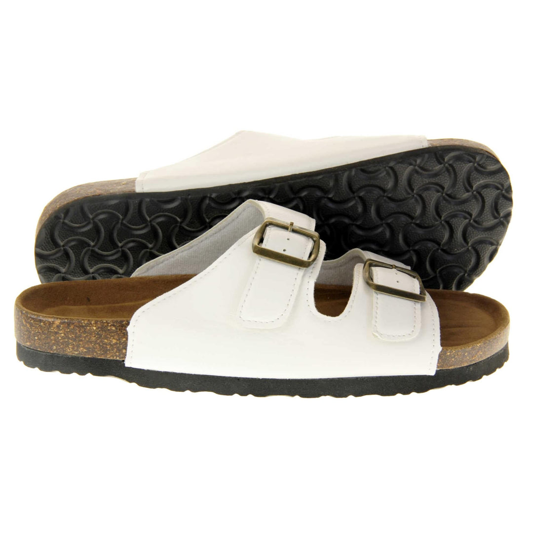 White flat sandals womens. Ladies dual strap slip on sandals. With a white synthetic leather upper with a gold buckle on each strap. Brown faux suede insole with a moulded footbed. Cork effect outsole with black base with grip to the bottom. Both feet from a side profile with the left foot on its side behind the the right foot to show the sole.