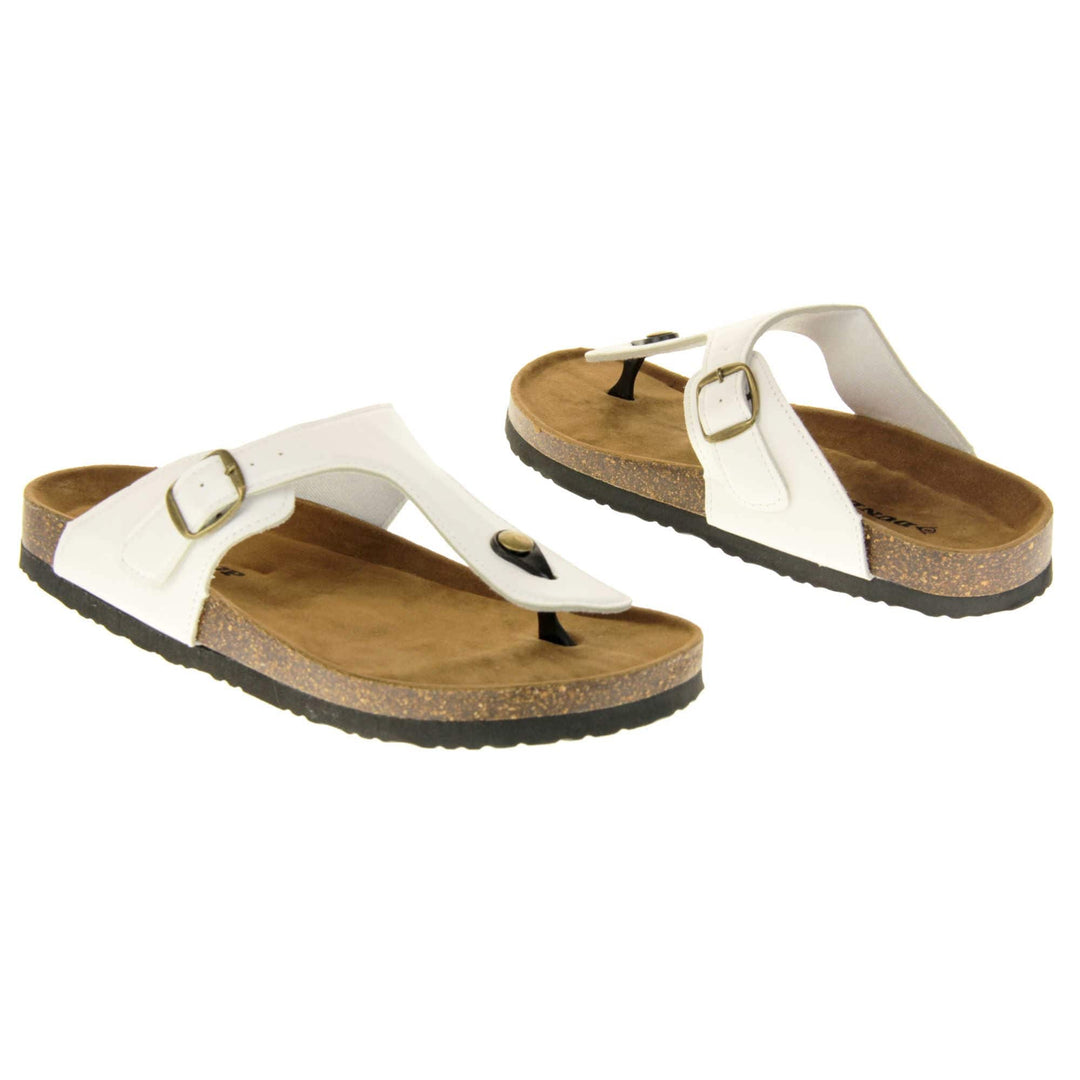 White toe post sandals. White faux leather strap with toe post to the front and gold buckle to the outside. Soft tan faux suede footbed with cork effect outsole and black sole. Both feet at an angle facing top to tail.