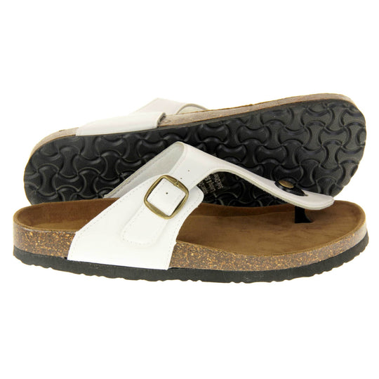 White toe post sandals. White faux leather strap with toe post to the front and gold buckle to the outside. Soft tan faux suede footbed with cork effect outsole and black sole. Both feet from a side profile with the left foot on its side behind the the right foot to show the sole.