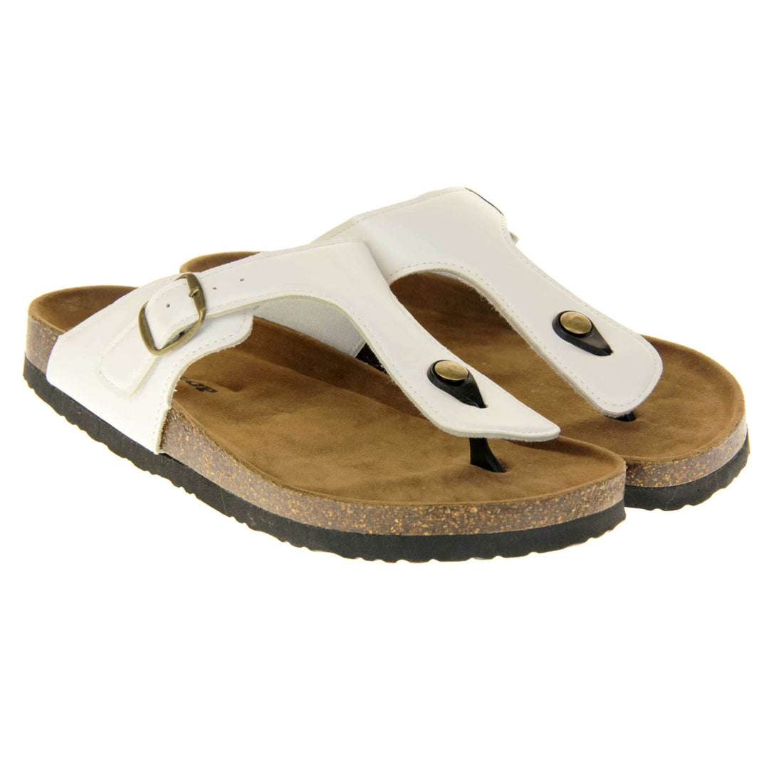 White toe post sandals. White faux leather strap with toe post to the front and gold buckle to the outside. Soft tan faux suede footbed with cork effect outsole and black sole. Both feet together at a slight angle.
