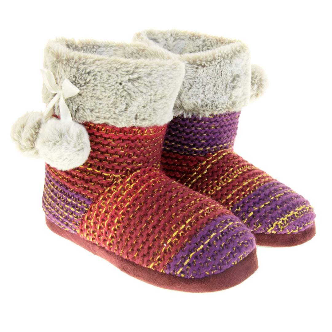 Womens knit slippers. Boot style slippers in a knit upper. Plum fading purple ombre effect with gold thread detailing. Light grey faux fur collar and lining with matching pom poms to the side. Both feet together at an angle