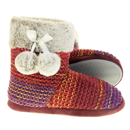 Womens knit slippers. Boot style slippers in a knit upper. Plum fading purple ombre effect with gold thread detailing. Light grey faux fur collar and lining with matching pom poms to the side. Both feet from a side profile with the left foot on its side behind the the right foot to show the sole.