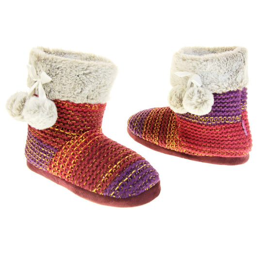 Womens knit slippers. Boot style slippers in a knit upper. Plum fading purple ombre effect with gold thread detailing. Light grey faux fur collar and lining with matching pom poms to the side. Both feet at an angle, facing top to tail.