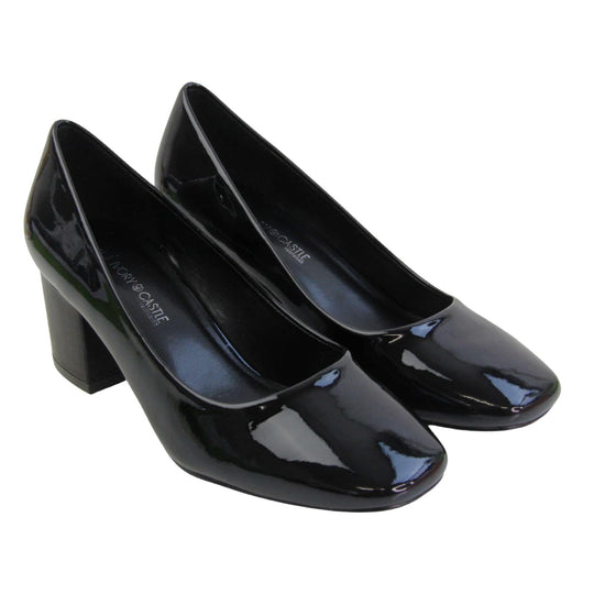 Womens black block heel. Womens court shoes with black patent faux leather uppers. Black block heel. Black faux leather lining with beige textile lining at the heel. Beige sole. Both feet together at an angle.