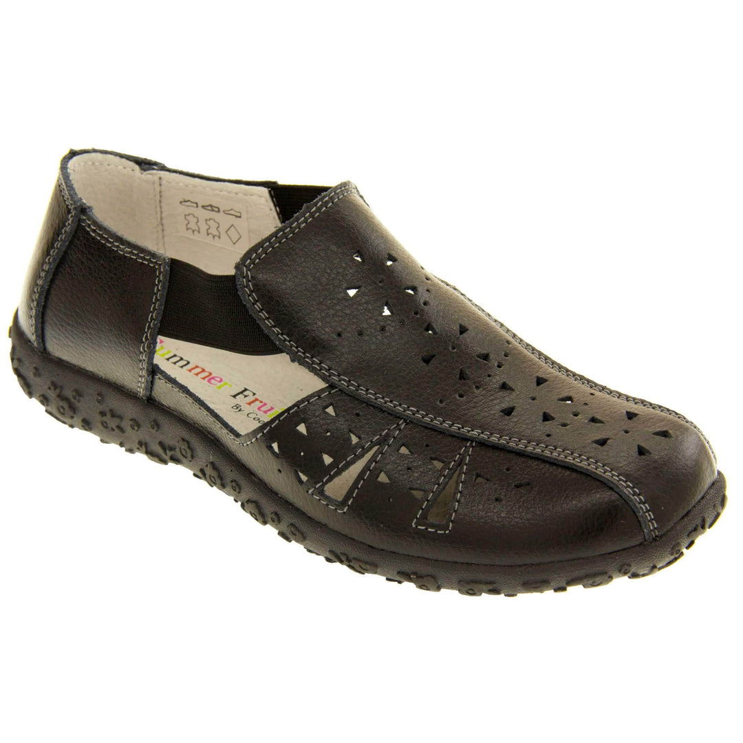 Womens black sandals. Black leather closed toe sandals with white stitched detailing. With small cut out details on the upper. Black elasticated strips from tongue to ankle to allow more room for a better fit. Cream coloured leather insole and lining. Black sole with heel having a slight platform with raised flower design for grip. Right foot at an angle.