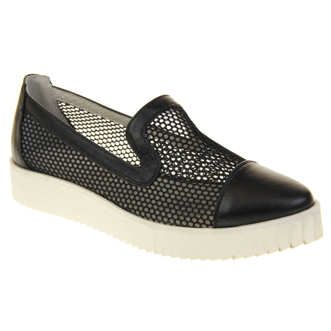 Womens flatforms. Loafer style shoes with a black net upper and black faux leather toe, heel and collar. White flat chunky platform. Cream insole. Right foot at an angle.