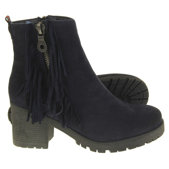 Women's fur lined winter boots. With a navy blue suede upper and zip fastening to the inside of the shoe. Decorate zip fastening to the outside with tassel detailing down the sides of the zip. Navy faux fur lining. A loop at the heel to help pull them on. Black outsole with chunky block heel.  Both feet from a side profile with the left foot on its side to show the sole.