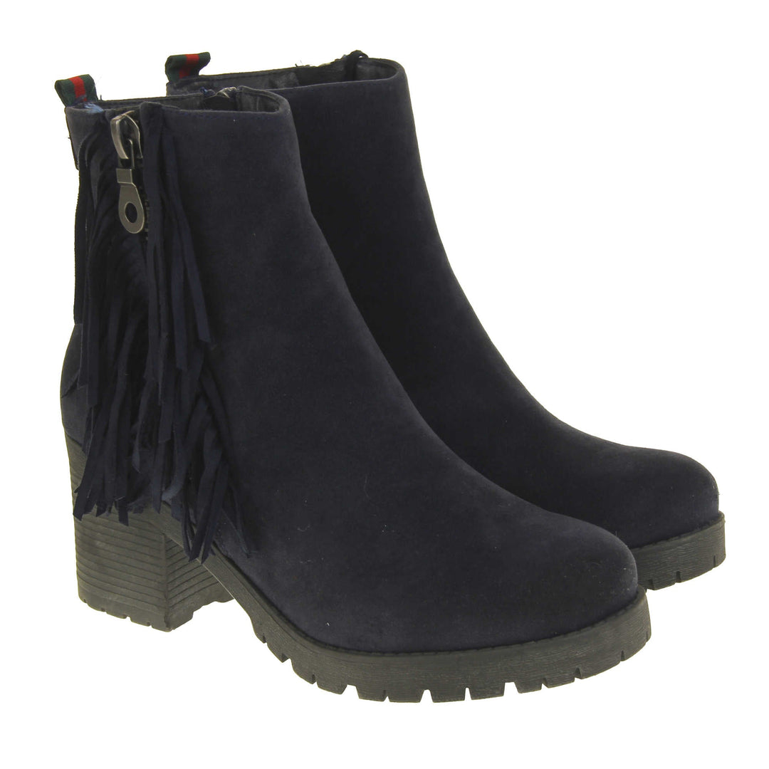 Women's fur lined winter boots. With a navy blue suede upper and zip fastening to the inside of the shoe. Decorate zip fastening to the outside with tassel detailing down the sides of the zip. Navy faux fur lining. A loop at the heel to help pull them on. Black outsole with chunky block heel. Both feet together from an angle.