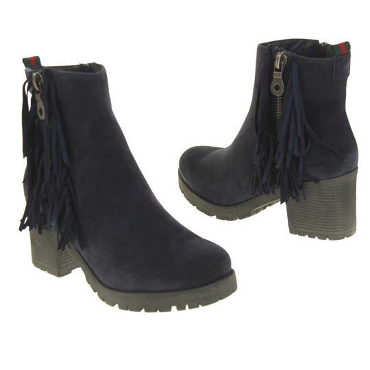 Women's fur lined winter boots. With a navy blue suede upper and zip fastening to the inside of the shoe. Decorate zip fastening to the outside with tassel detailing down the sides of the zip. Navy faux fur lining. A loop at the heel to help pull them on. Black outsole with chunky block heel. Both feet from a slight angle facing top to tail.