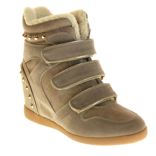 Women's wedge ankle boot. Ankle boot in a sneaker style with a grey faux suede upper. Wedge heel is hidden so the boots look flat. Three touch fasten straps across the front for fastening. Cream faux fur lining and trim. Gold studs around the collar and heel. Beige sole with good grip to the bottom. Right foot at an angle.
