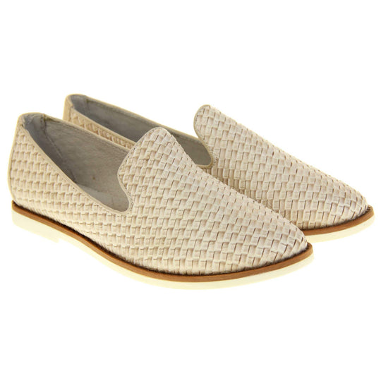 Womens beige loafers. Slip on loafer style shoe with a beige woven textile upper. Beige elasticated side gussets and plain beige textile around collar. White flat sole with brown line around the top and cream leather lining. Both feet together at a slight angle.
