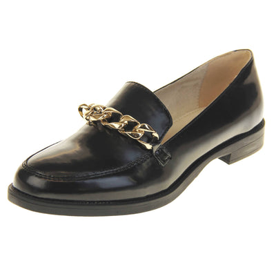 Womens black brogues. Loafer shoes in a Brogue style with a black faux leather upper. Gold chain detail over the tongue. Real leather lining. Black sole with a slight heel. Left foot at an angle.
