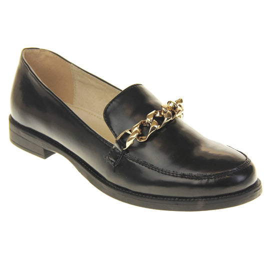 Womens black brogues. Loafer shoes in a Brogue style with a black faux leather upper. Gold chain detail over the tongue. Real leather lining. Black sole with a slight heel. Right foot at an angle.