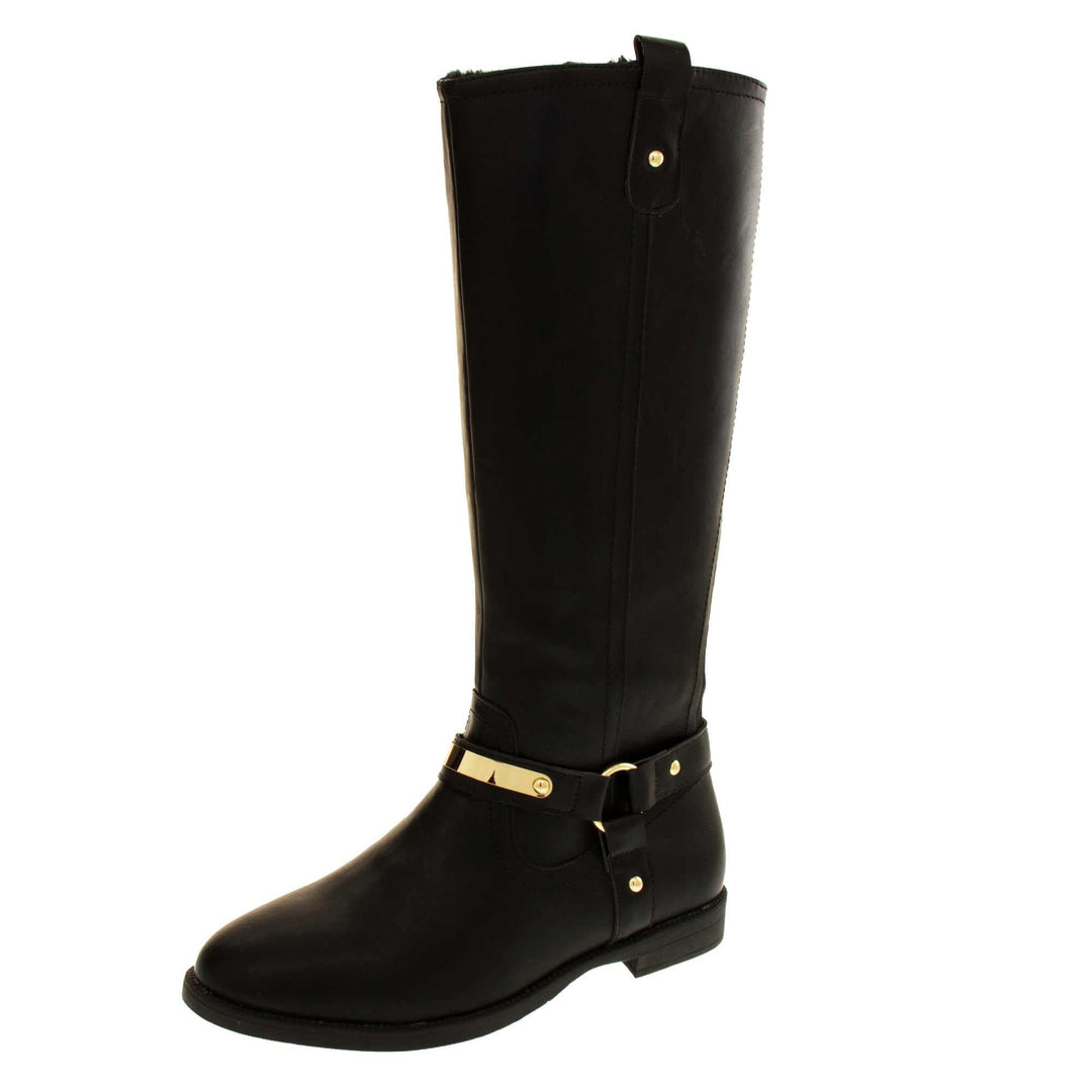 Womens black leather knee high boots. Knee high style boots with a black faux leather upper. A Tri strap going around the ankle and down to the bottom of the boot joined by the ankle with a good loop. Gold plate to the front of the ankle strap. Zip up the inside of the boot. Faux leather loop on the top of the outside of the boot to help with pulling it on. Left foot at an angle.