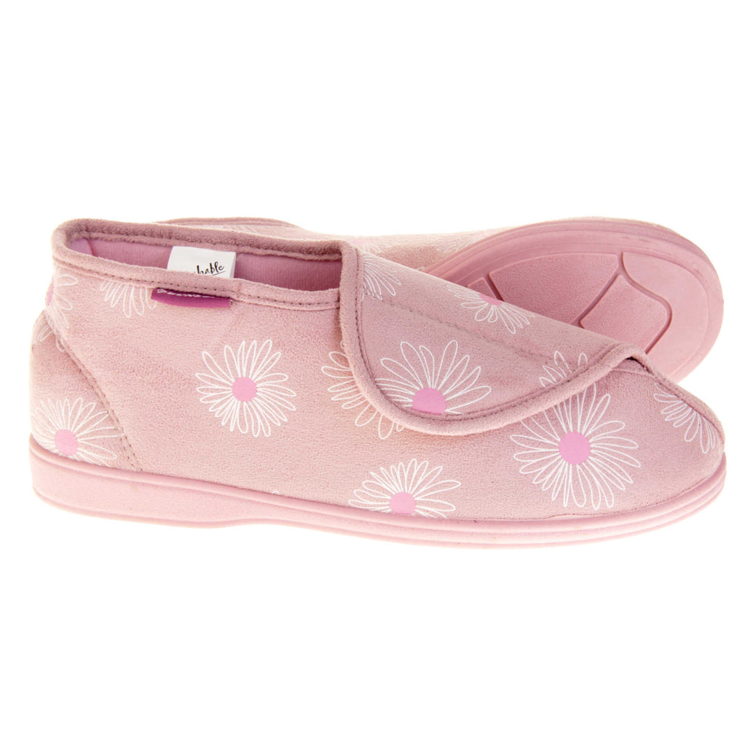 Womens bootie slippers. Ladies bootie style slipper with a pale pink textile upper with a white and pink flower print. Touch fasten tab to the top and pink textile lining. Firm pink sole. Both feet from a side profile with the left foot on its side behind the the right foot to show the sole.