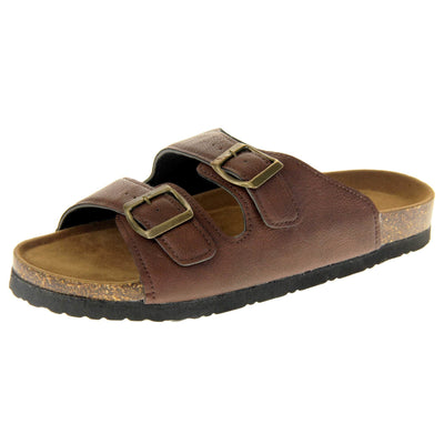 Womens brown slide sandals. Ladies dual strap slip on sandals. With a brown synthetic leather upper with a gold buckle on each strap. Brown faux suede insole with a moulded footbed. Cork effect outsole with black base with grip to the bottom. Left foot at an angle.