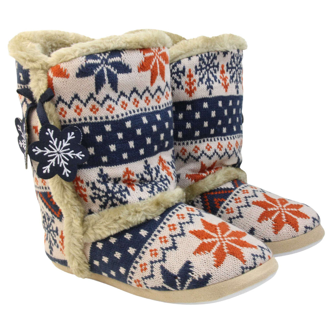 Womens Christmas Slipper Boots - Blue, beige and brown snowflake knitted upper with beige fur lining and trim. Navy blue and white snowflake shaped tassels to side. Both feet together at angle.