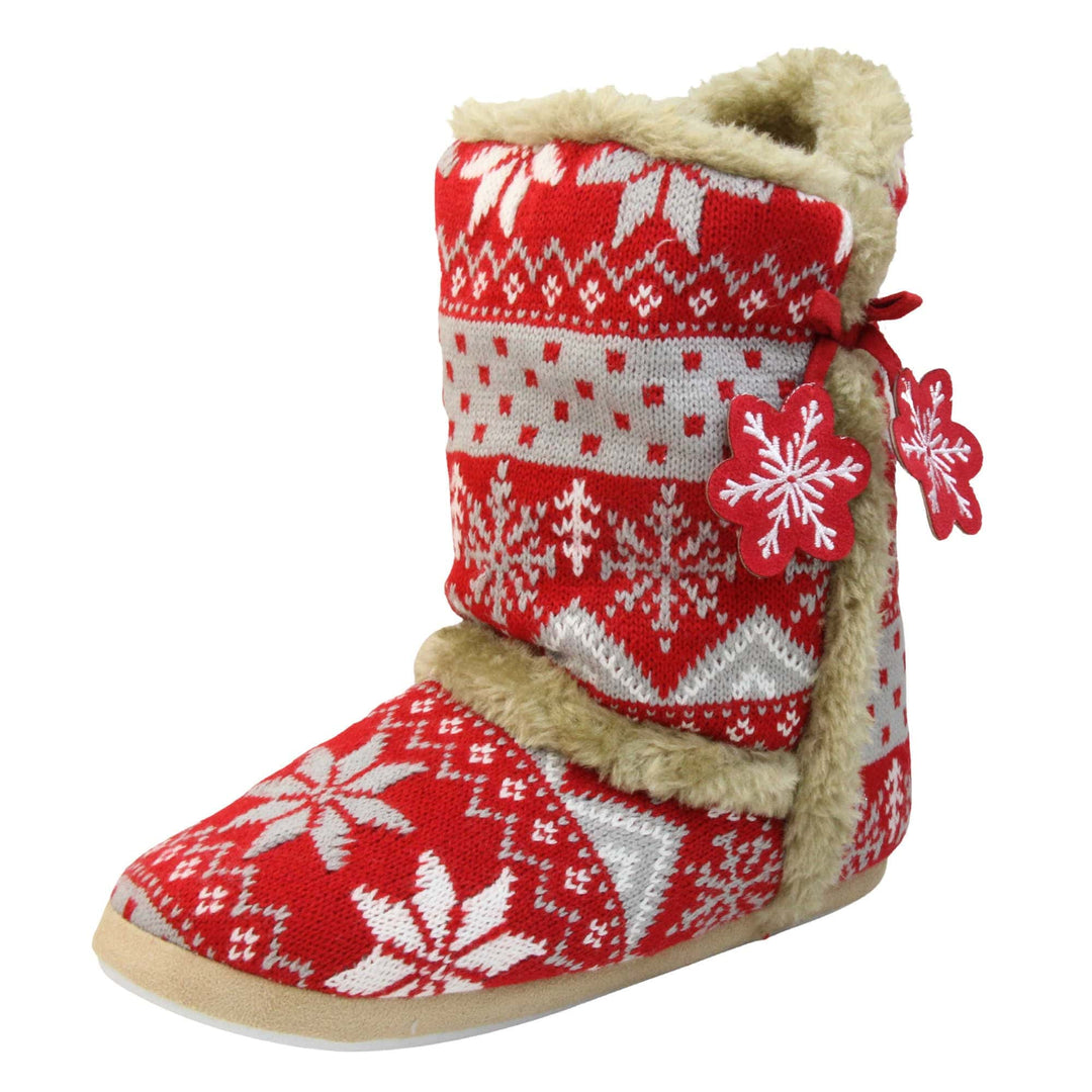 Womens Christmas Slippers - Red snowflake knitted upper with beige fur lining and trim. Two snowflake shaped tassels to the side. Left foot at angle.