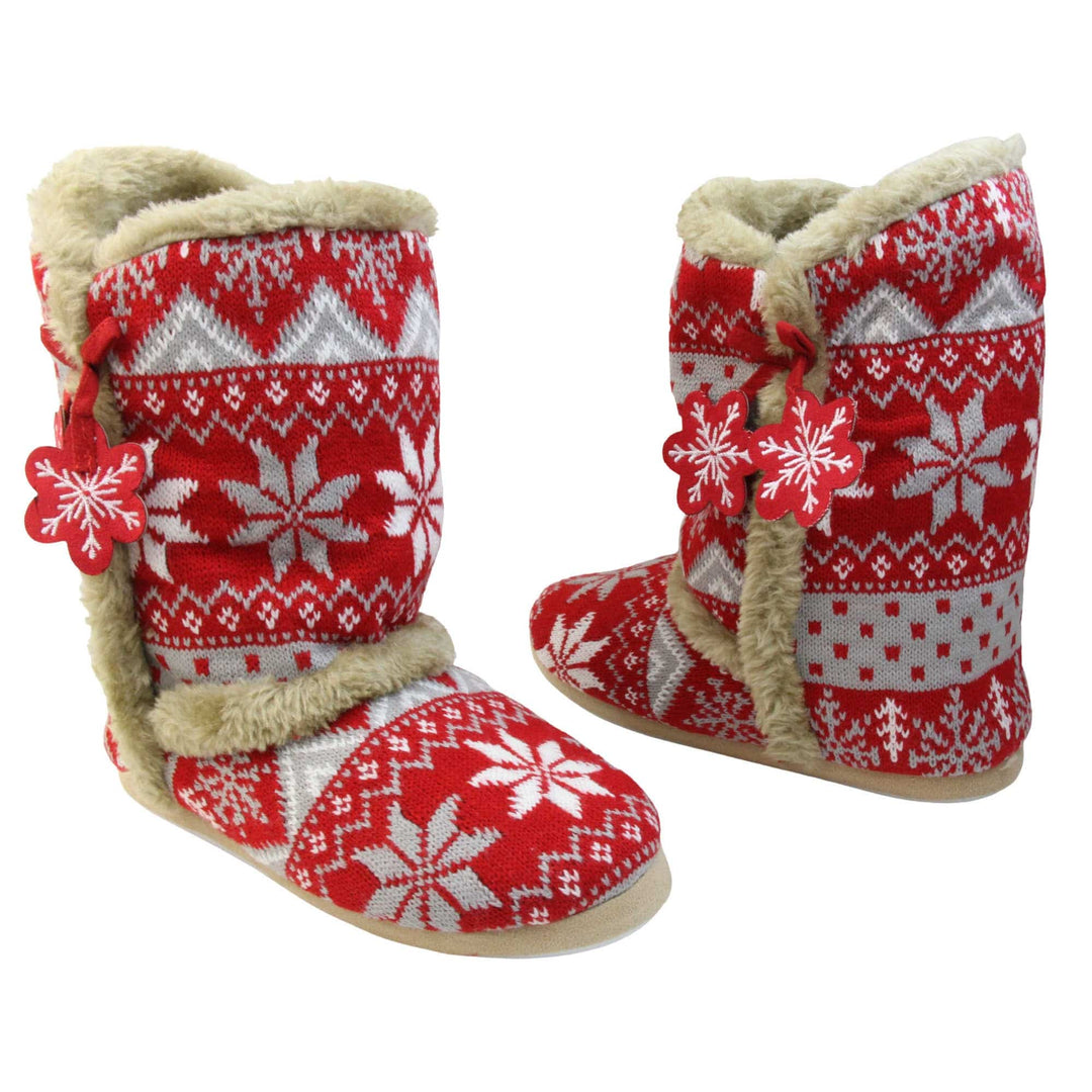Womens Christmas Slippers - Red snowflake knitted upper with beige fur lining and trim. Two snowflake shaped tassels to the side. Both feet at an angle facing top to tail.