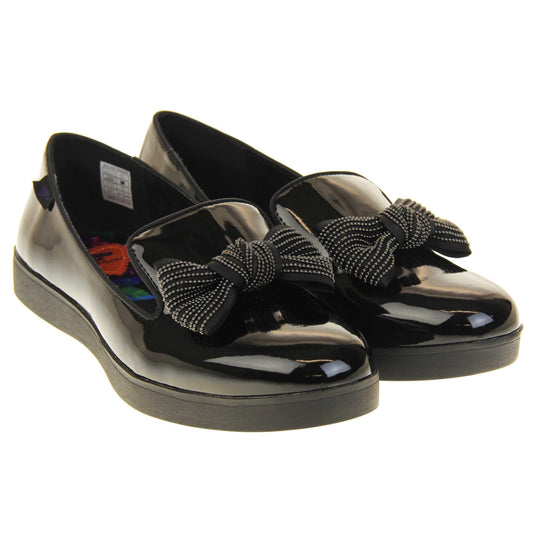 Women's comfortable loafers. Loafer style shoes with a black faux patent leather upper. With a black bow detail on the top of the foot. Bright floral patterned insole. Chunky black sole with slip resistant grip to the bottom. Both feet together at a slight angle.