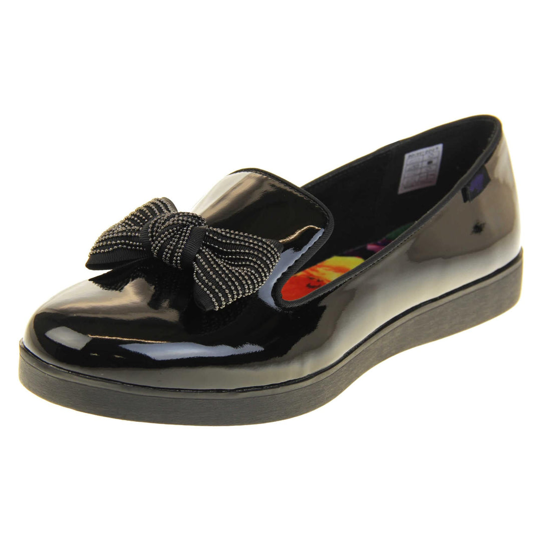 Women's comfortable loafers. Loafer style shoes with a black faux patent leather upper. With a black bow detail on the top of the foot. Bright floral patterned insole. Chunky black sole with slip resistant grip to the bottom. Left foot at an angle.