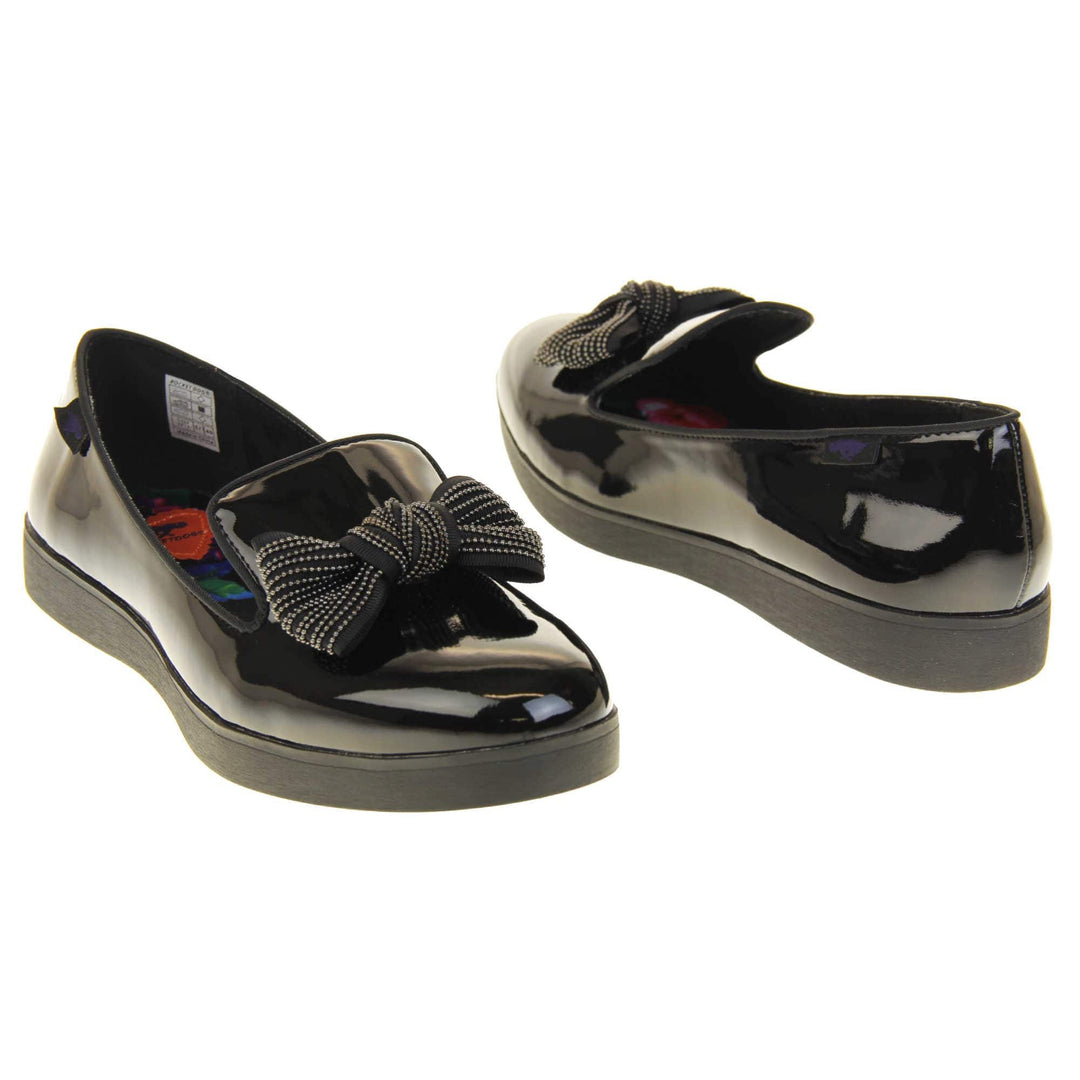 Women's comfortable loafers. Loafer style shoes with a black faux patent leather upper. With a black bow detail on the top of the foot. Bright floral patterned insole. Chunky black sole with slip resistant grip to the bottom. Both feet at an angle facing top to tail.