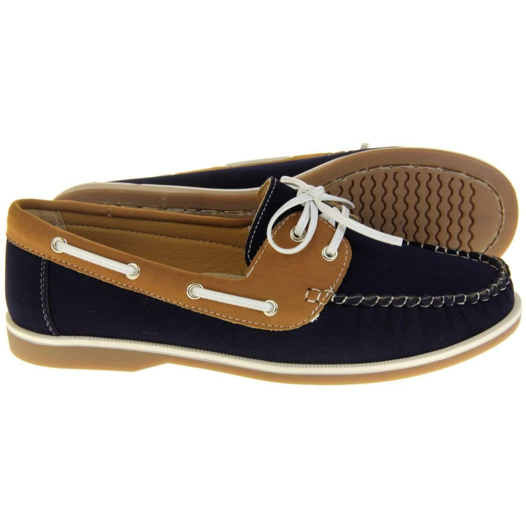 Womens Deck Shoes - Navy blue and tan brown faux leather upper with white rim around the tan sole. Leather effect cord strips with eyelets detailing down the side of the shoe with lace up fastening to the front. Side angle, and sole facing.