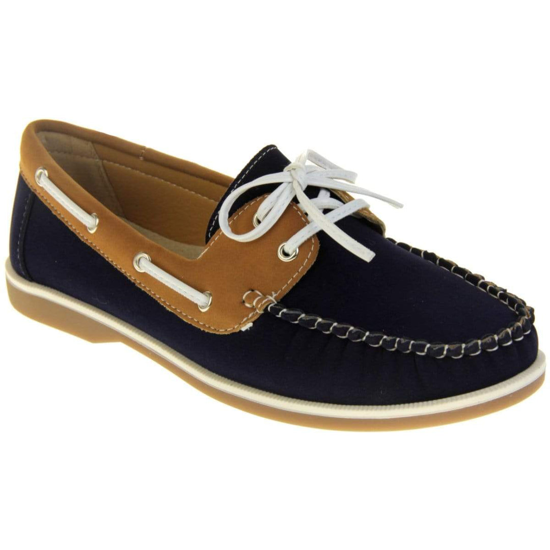 Womens Deck Shoes - Navy blue and tan brown faux leather upper with white rim around the tan sole. Leather effect cord strips with eyelets detailing down the side of the shoe with lace up fastening to the front. Right angle facing.