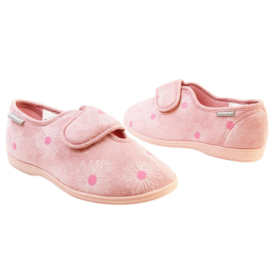 Pink flower slippers. Womens full back slipper. With a pale pink upper with white daisy design with bright pink for the middle of the flowers. Touch fasten strap over the top of the foot to adjust the fit. Pink textile lining and firm pink sole. Both feet at an angle, facing top to tail.