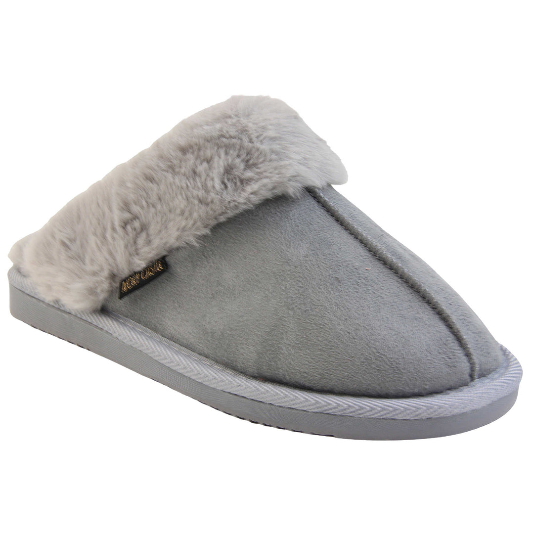 Womens faux fur mule slippers. Slip on style slippers with light grey faux suede uppers. Light grey faux fur lining and collar. Firm grey outsole with grip on the bottom. Right foot at an angle.