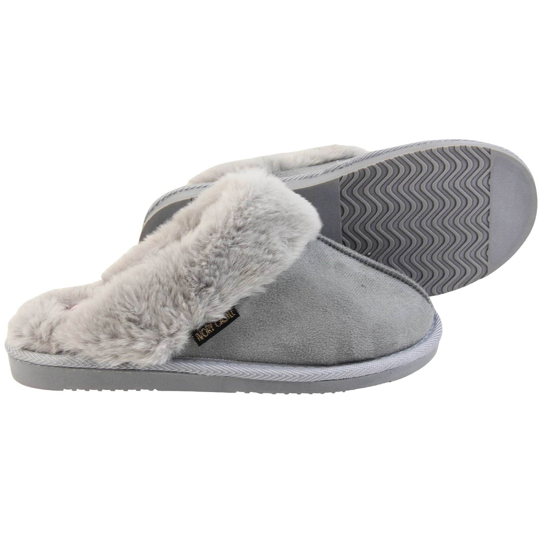 Womens faux fur mule slippers. Slip on style slippers with light grey faux suede uppers. Light grey faux fur lining and collar. Firm grey outsole with grip on the bottom. Both feet from a side profile with the left foot on its side behind the the right foot to show the sole.