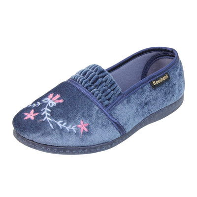 Womens full slippers. Full back slippers in a loafer style. With light blue velour uppers and an embroidered pale blue and pink flower detail. Ruched velour elasticated gusset. Blue textile lining and piping around the collar. Blue firm sole. Left foot at an angle.